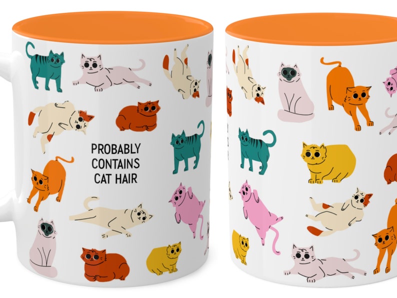 May include: White ceramic mug with an orange rim. The mug features a repeating pattern of colourful cartoon cats in various poses. The text "Probably Contains Cat Hair" is printed in black on the mug.
