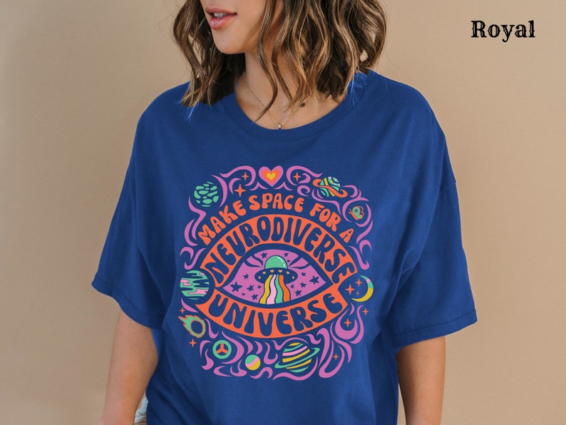 May include: A royal blue t-shirt featuring a colourful graphic design that reads "Make space for a neurodiverse universe". The graphic depicts a psychedelic eye with a spaceship, stars, and planets.