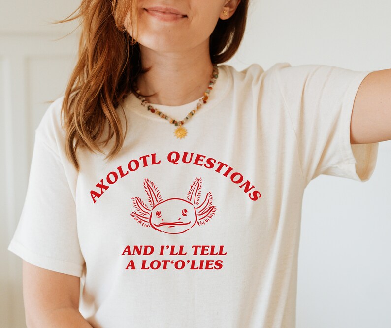 May include: A white t-shirt with a red axolotl graphic and the text "Axolotl Questions and I'll Tell A Lot O' Lies".
