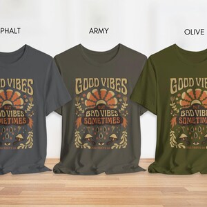May include: Three t-shirts in different colors: asphalt, army, and olive. Each shirt features a graphic design with the text "Good Vibes But Bad Vibes Sometimes".