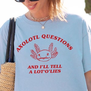 May include: Light blue t-shirt with a red axolotl graphic and the text "Axolotl Questions and I'll Tell A Lot'o'Lies".