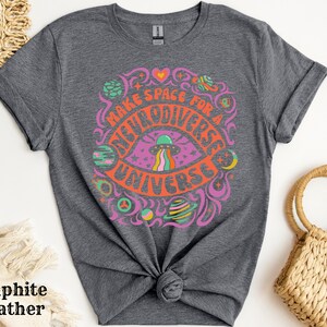 May include: A dark grey t-shirt with a colourful graphic design featuring a psychedelic eye with a UFO and the text "Make Space For A Multiverse Universe".