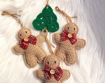 May include: Three crocheted Christmas ornaments: a green tree and two gingerbread people with red and black plaid bows and brown buttons.