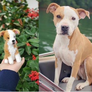 May include: A crocheted dog toy, brown and white, with a realistic appearance, is held in a person's hand. A real dog, brown and white, sits on a boat.
