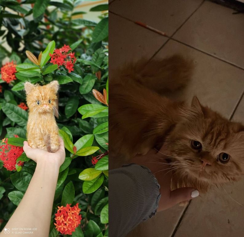 May include: A close-up of a small, orange knitted cat toy. The toy is being held in a person's hand. The background is a green bush with red flowers.