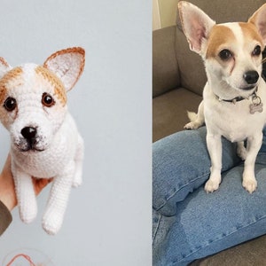 May include: A crocheted stuffed dog toy with brown and white fur, sitting in a person's hand. The dog has a white collar with a silver tag.