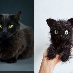May include: A black cat with green eyes sits on a gray surface. Next to it is a black crocheted cat toy with green eyes, held in a hand.