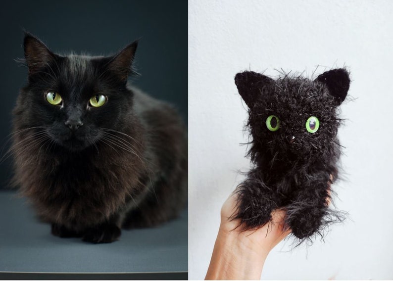 May include: A black cat with green eyes sits on a gray surface. Next to it is a black crocheted cat toy with green eyes, held in a hand.