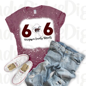 May include: A maroon t-shirt with a bleached design featuring the numbers 606, a stylized hornet, and the text "Magoffin County Hornets".