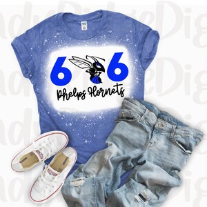 May include: A blue t-shirt with a white splatter design. The shirt has a blue and black hornet graphic with the text "606 Phelps Hornets" printed on it.