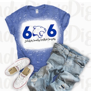 May include: A blue t-shirt with a white bleach design featuring the number 606, a panther mascot, and the text "Letcher County Central Cougars".