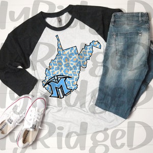 May include: A white and black baseball tee shirt with a blue and tan leopard print design of the state of West Virginia. The shirt has a black sleeve and a white sleeve. A blue and white logo with the letter "M" is on the shirt. A pair of blue jeans and white sneakers are also in the image.