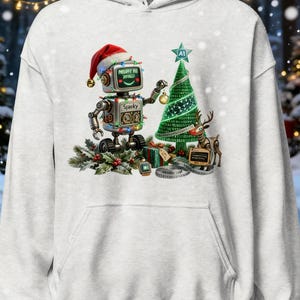 May include: A light gray hooded sweatshirt featuring a graphic of a robot wearing a Santa hat, decorated with colorful string lights, placing an ornament on a green Christmas tree. The robot has the name Sparky and text Merry AI Xmas.