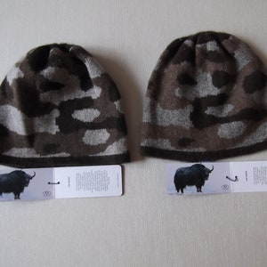 May include: Two brown and gray camouflage knit hats with a black yak on the tag. The tag also has the text "Yak Edition".