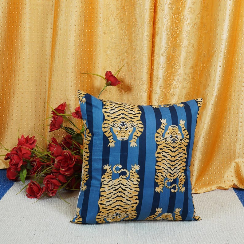 May include: A blue and yellow striped throw pillow with a tiger print design. The pillow is decorated with three tigers in a standing position.
