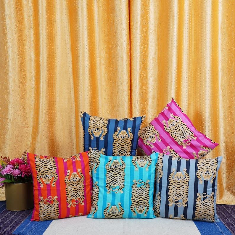 May include: Five decorative throw pillows with a striped pattern and a tiger design. The pillows are in shades of blue, pink, orange, and turquoise.