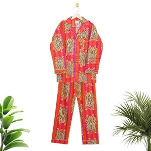 "Vibrant orange and pink vertical striped pajama set featuring a repeating tiger animal print. This 4-piece women's cotton nightwear collection includes a long-sleeve button-down shirt with collar and piping, full-length pajama pants, matching shorts, and a fabric envelope pouch. Indian block print style loungewear perfect for boho bridesmaid gifts, bachelorette parties, or summer sleepwear. Soft breathable fabric with funky safari design."