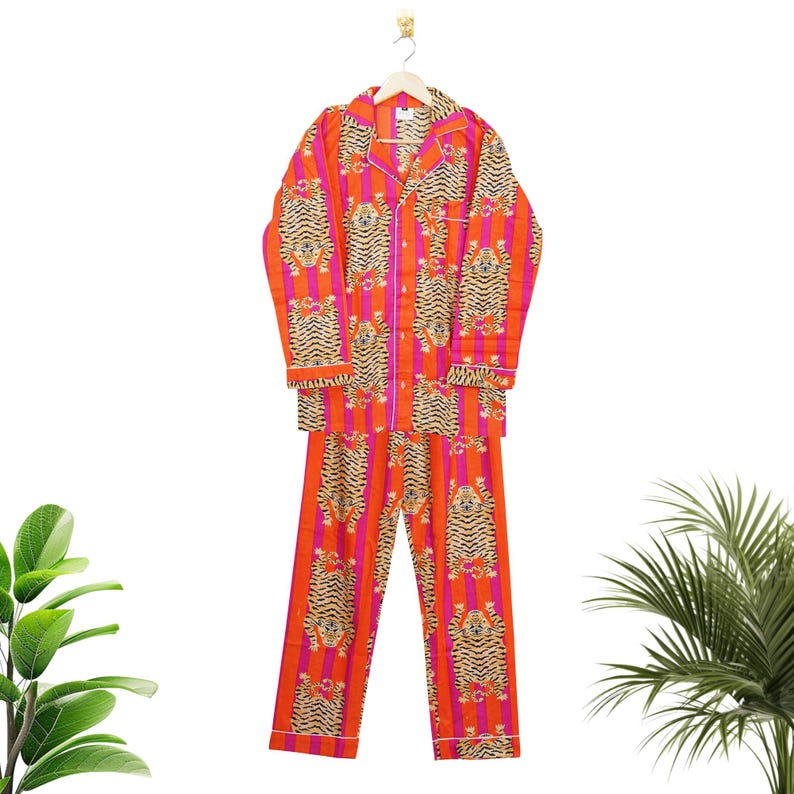 "Vibrant orange and pink vertical striped pajama set featuring a repeating tiger animal print. This 4-piece women's cotton nightwear collection includes a long-sleeve button-down shirt with collar and piping, full-length pajama pants, matching shorts, and a fabric envelope pouch. Indian block print style loungewear perfect for boho bridesmaid gifts, bachelorette parties, or summer sleepwear. Soft breathable fabric with funky safari design."