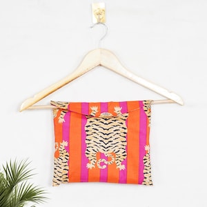 "Vibrant orange and pink vertical striped pajama set featuring a repeating tiger animal print. This 4-piece women's cotton nightwear collection includes a long-sleeve button-down shirt with collar and piping, full-length pajama pants, matching shorts, and a fabric envelope pouch. Indian block print style loungewear perfect for boho bridesmaid gifts, bachelorette parties, or summer sleepwear. Soft breathable fabric with funky safari design."