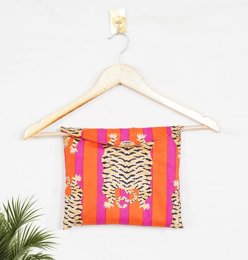 "Vibrant orange and pink vertical striped pajama set featuring a repeating tiger animal print. This 4-piece women's cotton nightwear collection includes a long-sleeve button-down shirt with collar and piping, full-length pajama pants, matching shorts, and a fabric envelope pouch. Indian block print style loungewear perfect for boho bridesmaid gifts, bachelorette parties, or summer sleepwear. Soft breathable fabric with funky safari design."