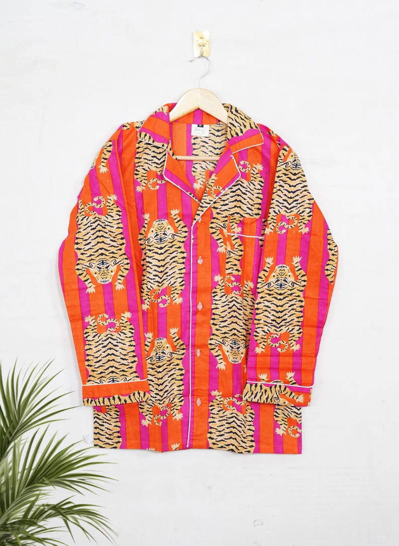 "Vibrant orange and pink vertical striped pajama set featuring a repeating tiger animal print. This 4-piece women's cotton nightwear collection includes a long-sleeve button-down shirt with collar and piping, full-length pajama pants, matching shorts, and a fabric envelope pouch. Indian block print style loungewear perfect for boho bridesmaid gifts, bachelorette parties, or summer sleepwear. Soft breathable fabric with funky safari design."