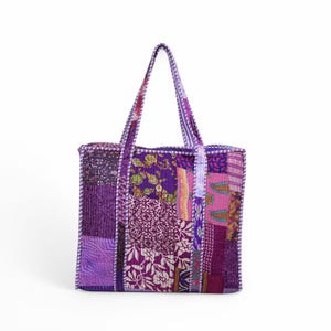 May include: A purple patchwork tote bag with a white trim. The bag is made of different fabrics with floral and paisley patterns.