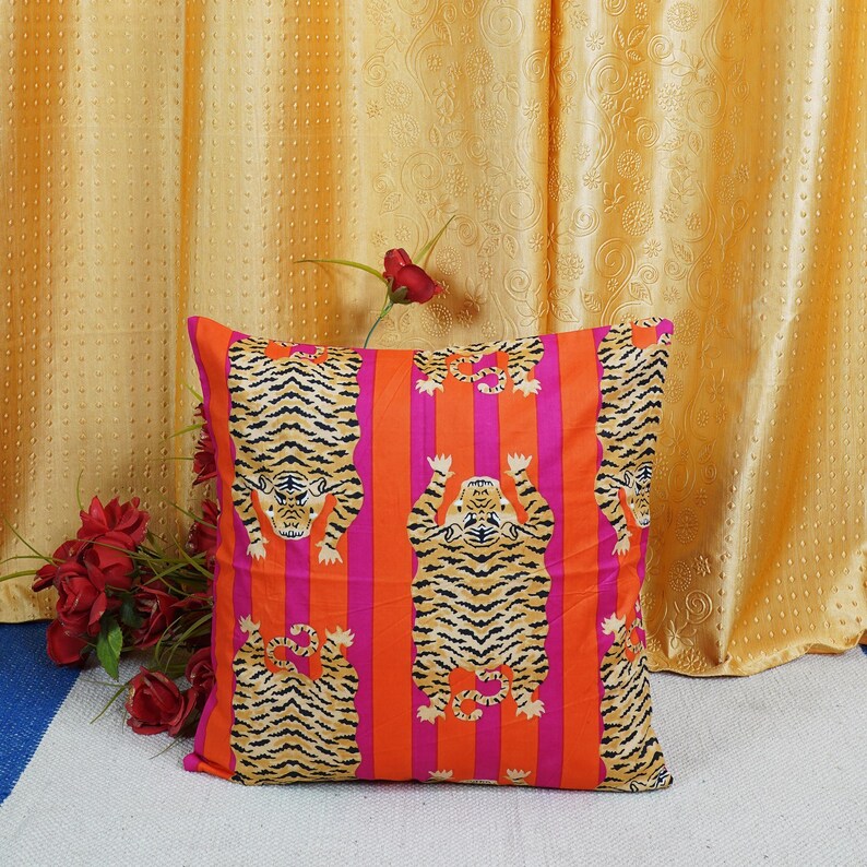 May include: A square throw pillow with a bright orange and pink striped background. The pillow features a repeating pattern of black and orange tigers in an upside-down position.