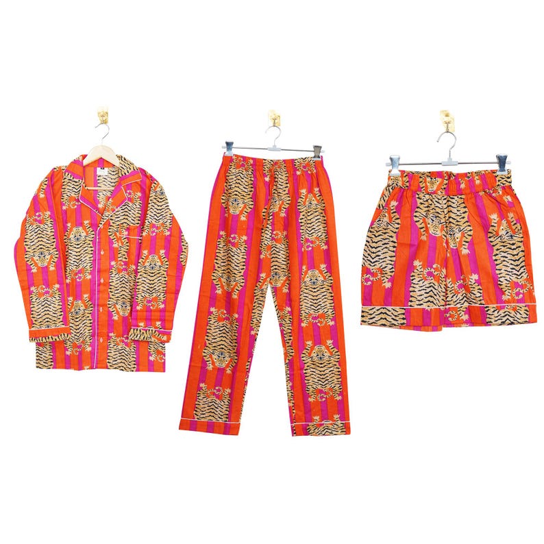 "Vibrant orange and pink vertical striped pajama set featuring a repeating tiger animal print. This 4-piece women's cotton nightwear collection includes a long-sleeve button-down shirt with collar and piping, full-length pajama pants, matching shorts, and a fabric envelope pouch. Indian block print style loungewear perfect for boho bridesmaid gifts, bachelorette parties, or summer sleepwear. Soft breathable fabric with funky safari design."