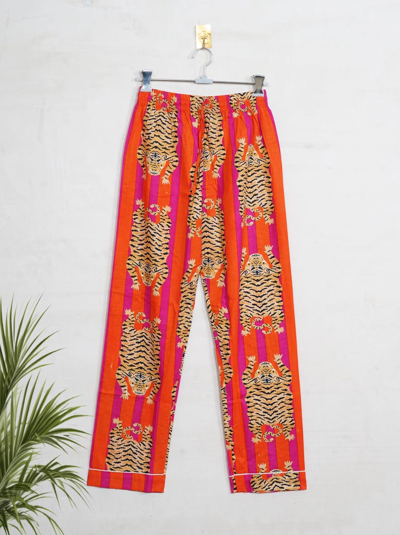 "Vibrant orange and pink vertical striped pajama set featuring a repeating tiger animal print. This 4-piece women's cotton nightwear collection includes a long-sleeve button-down shirt with collar and piping, full-length pajama pants, matching shorts, and a fabric envelope pouch. Indian block print style loungewear perfect for boho bridesmaid gifts, bachelorette parties, or summer sleepwear. Soft breathable fabric with funky safari design."