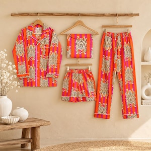 Può includere: Un set di pigiama composto da una camicia a maniche lunghe con bottoni, un paio di pantaloncini e un paio di pantaloni lunghi, realizzati in tessuto con un vivace motivo a righe verticali arancioni e rosa e una stampa di tigre ripetuta.