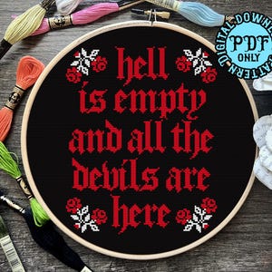 May include: A black cross-stitch hoop with the phrase "hell is empty and all the devils are here" in red gothic lettering. The design includes floral accents. Embroidery floss in various colors surrounds the hoop.