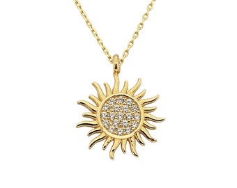 May include: A gold necklace with a sun pendant. The pendant is covered in small, clear stones.