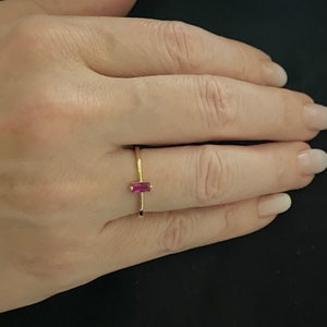 May include: A gold ring with a pink rectangular gemstone.