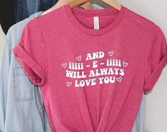 May include: Pink t-shirt with white text that reads "AND - E - WILL ALWAYS LOVE YOU" with hearts around the text.