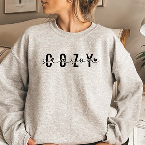 May include: Gray sweatshirt with the text "Cozy Season" in black lettering with a small heart.