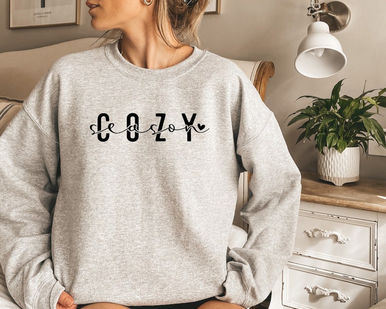 May include: Gray sweatshirt with the text "Cozy Season" in black lettering with a small heart.