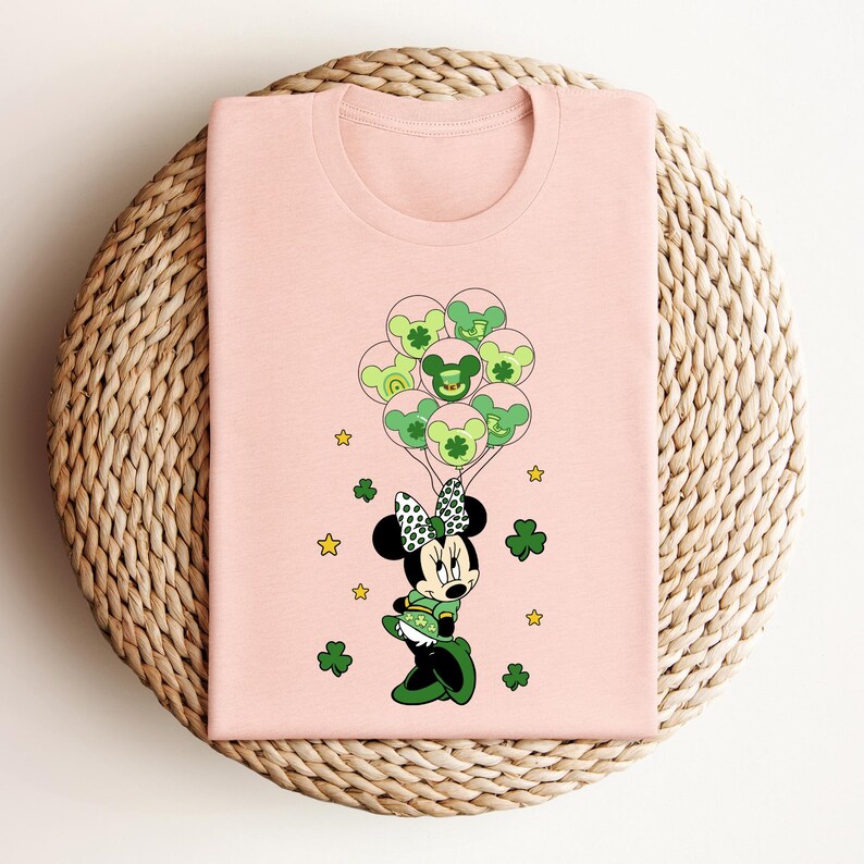 a pink shirt with a mickey mouse holding shamrocks