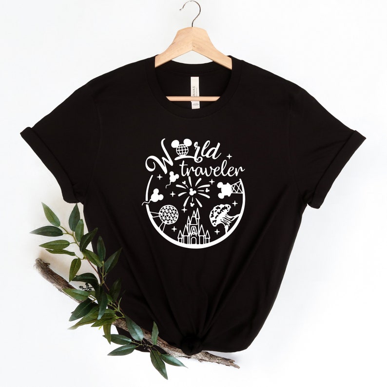 May include: Black t-shirt with a white graphic design. The design features the words "World traveler" in a circular arrangement with iconic travel-themed illustrations, including a castle, fireworks, and a globe.