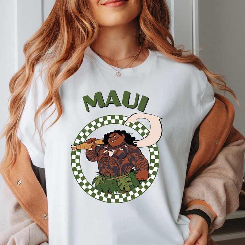 a woman wearing a white shirt with an image of a man holding a gun.


Moana Maui Shirt, Disney Maui Costume
