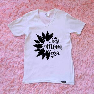 Op de afbeelding: Wit T-shirt met een zwart zonnebloemontwerp en de tekst "best mom ever".