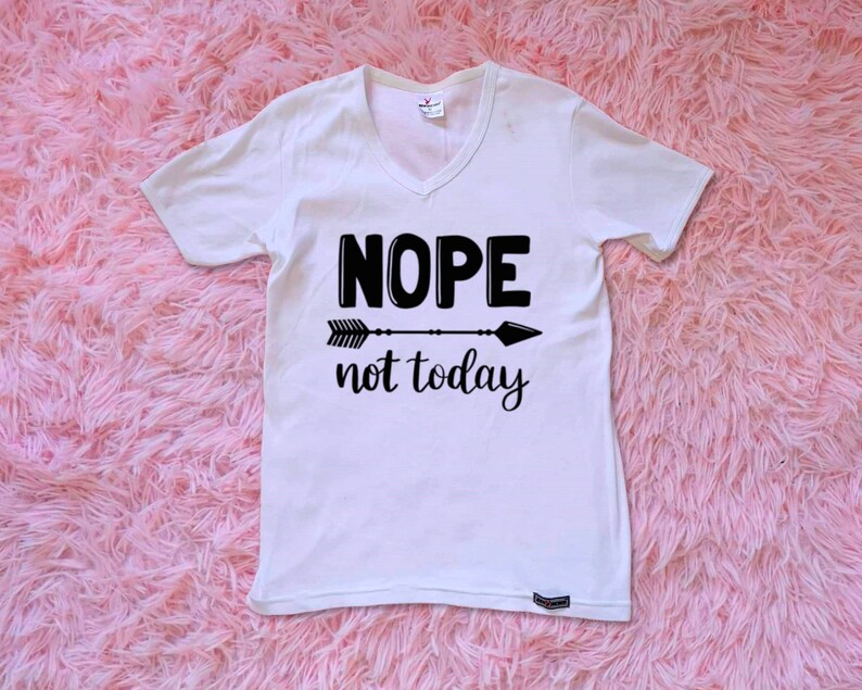 May include: White v-neck t-shirt with black text that reads "NOPE not today" and a black arrow graphic.