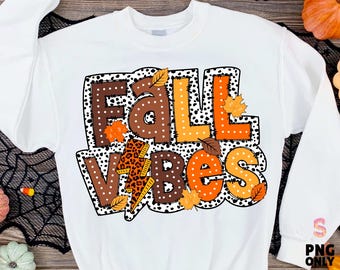 May include: White sweatshirt with the words "Fall Vibes" in a colorful, fall-themed design. The text features brown, orange, and yellow letters with a leopard print accent and autumn leaves.