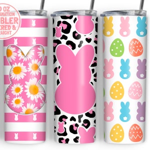 May include: Three 20 oz sublimation tumblers with different Easter-themed designs. The first tumbler has a pink and white striped background with a pink bunny silhouette filled with white daisies. The second tumbler has a pink bunny silhouette on a black and white leopard print background. The third tumbler has a white background with a repeating pattern of pink, blue, purple, and yellow bunnies and green, yellow, and orange eggs.
