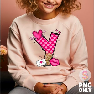 K&ouml;nnte beinhalten: Ein rosa Sweatshirt mit einem Aufdruck des Buchstabens Y, der aus rosa Herzen und Glitzer besteht. Der Aufdruck enth&auml;lt auch einen kleinen Umschlag, ein Herz und einen Pfeil.