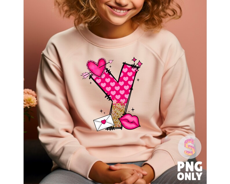 K&ouml;nnte beinhalten: Ein rosa Sweatshirt mit einem Aufdruck des Buchstabens Y, der aus rosa Herzen und Glitzer besteht. Der Aufdruck enth&auml;lt auch einen kleinen Umschlag, ein Herz und einen Pfeil.