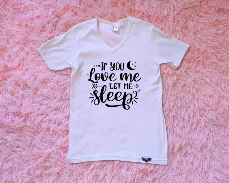 May include: White V-neck t-shirt with black text that reads "...If you love me let me sleep". The text includes a crescent moon and stars.