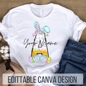 Puede incluir: Camiseta blanca con una letra A de purpurina dorada decorada con huevos de Pascua pastel, flores y un conejito azul con orejas rosas. El texto "Your Name" está escrito encima de la letra. Diseño de Canva editable.