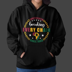 Pu&ograve; includere: Felpa con cappuccio nera con un design a catena dorata e il testo "Juneteenth breaking every chain since 1865". Il design include anche un contorno rosso, giallo e verde dell'Africa con un pugno alzato.