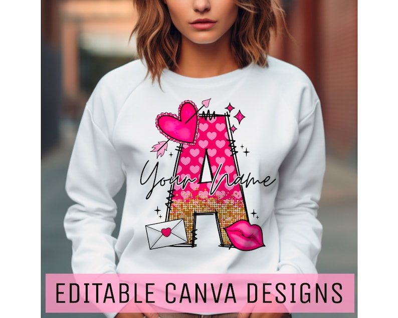 K&ouml;nnte beinhalten: Wei&szlig;er Pullover mit einem pinkfarbenen und goldenen Glitzerbuchstaben A, einem pinkfarbenen Herzen mit einem Pfeil durch und dem Text "Your Name".