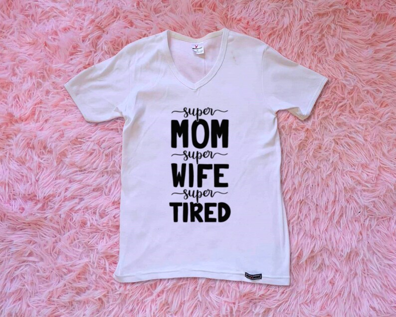 Op de afbeelding: Wit T-shirt met V-hals en zwarte tekst die "super mama super vrouw super moe" luidt.